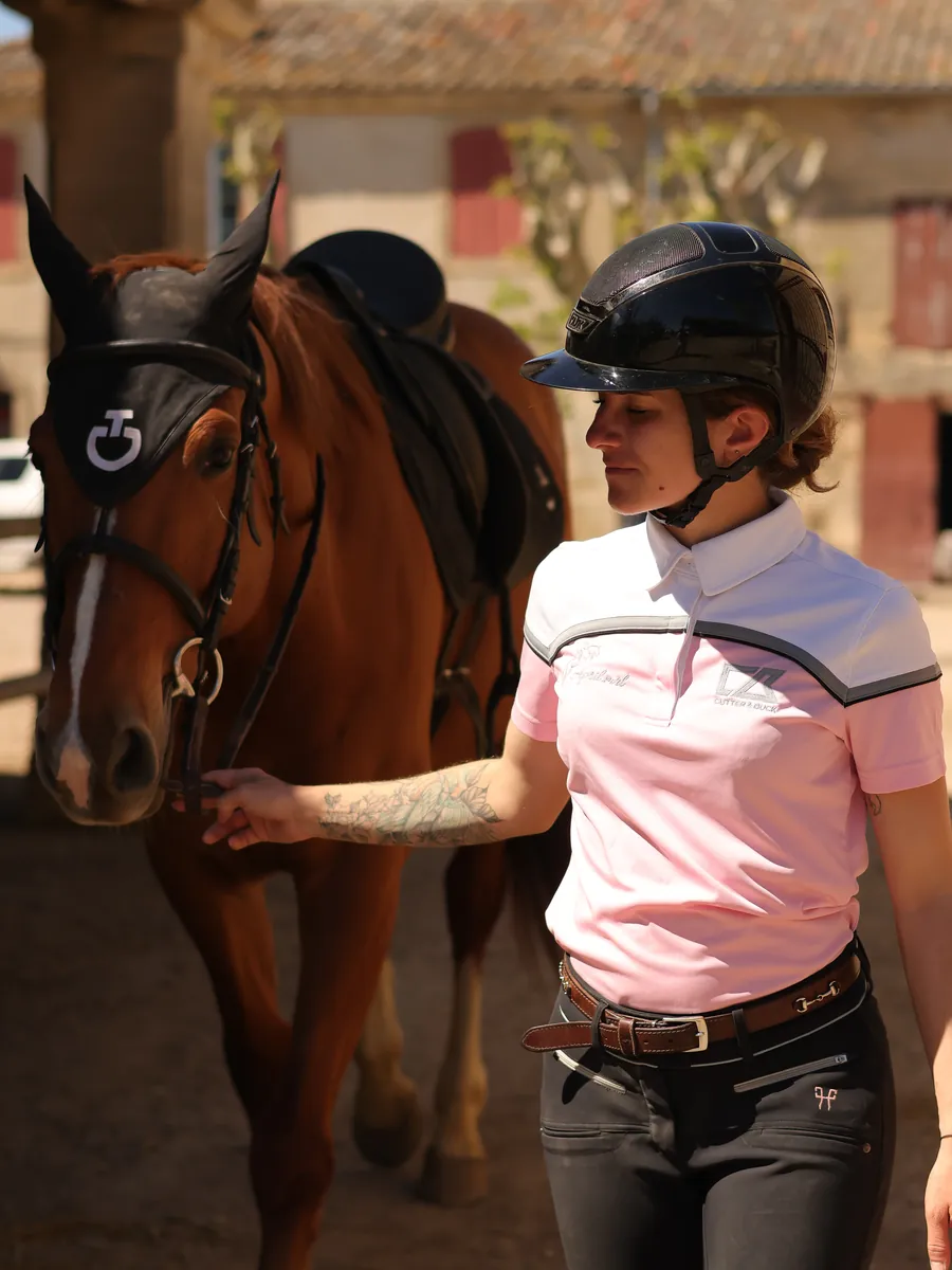 April Morel, casquée, tient en main un cheval alezan